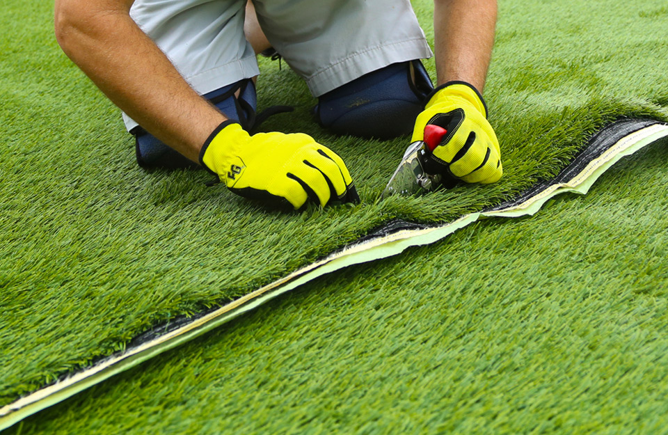 Close up of artificial grass installer cutting turf